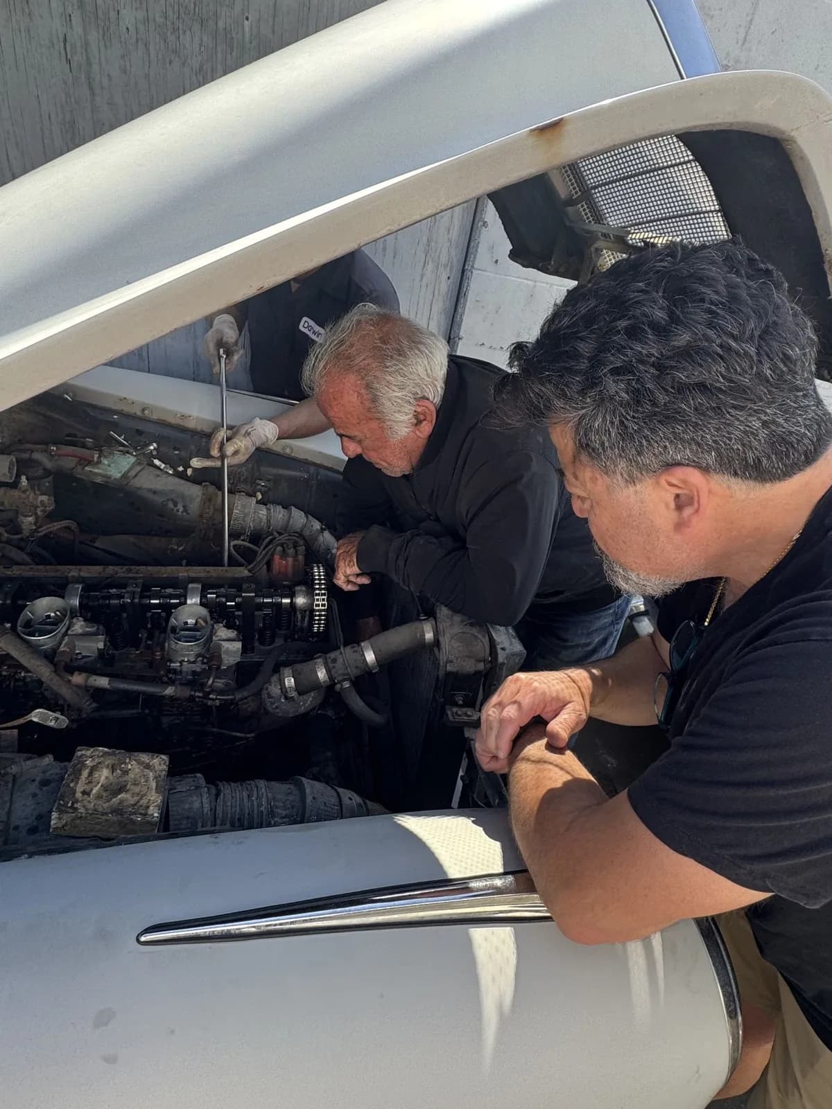 Mike and Darwin working under the hood of a classic Mercedes
