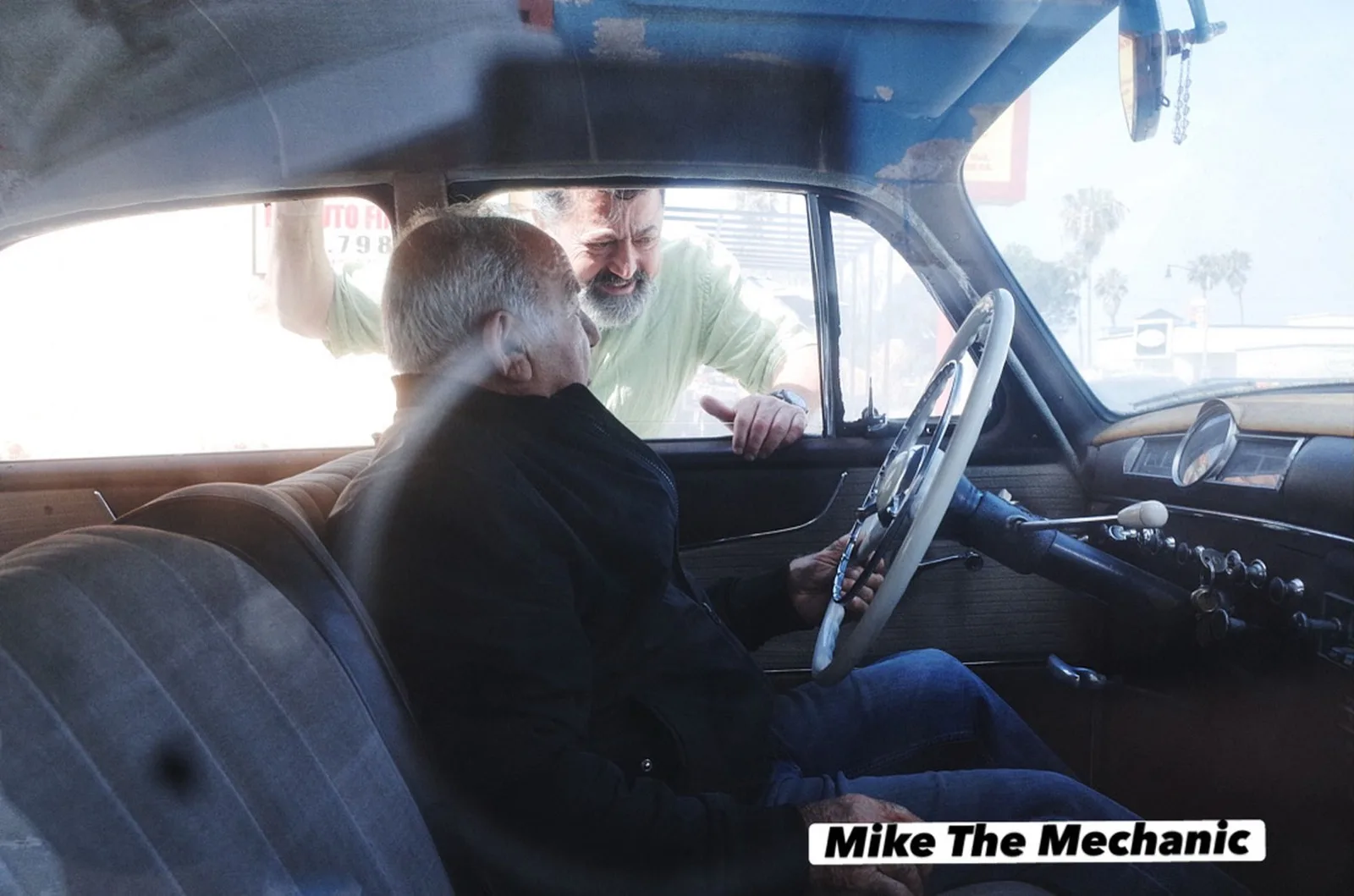 Mike behind the wheel of a classic Mercedes with a customer
